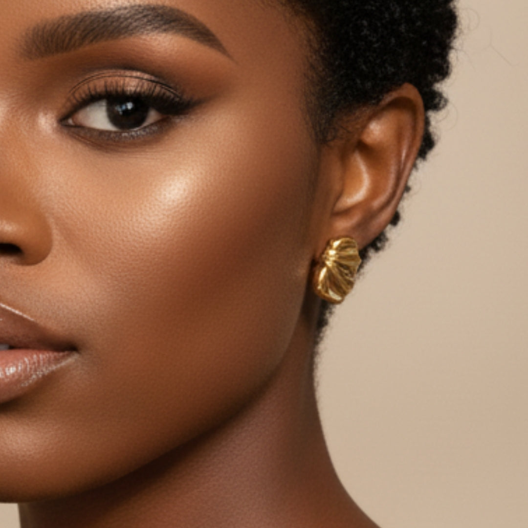 Close-up of a woman wearing gold earrings with a neutral background