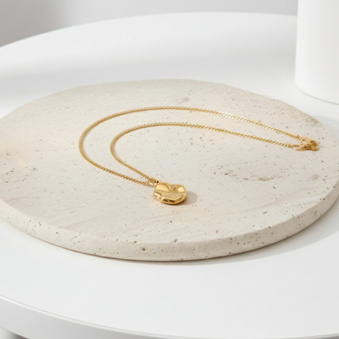 Gold necklace on a textured stone surface with a white background