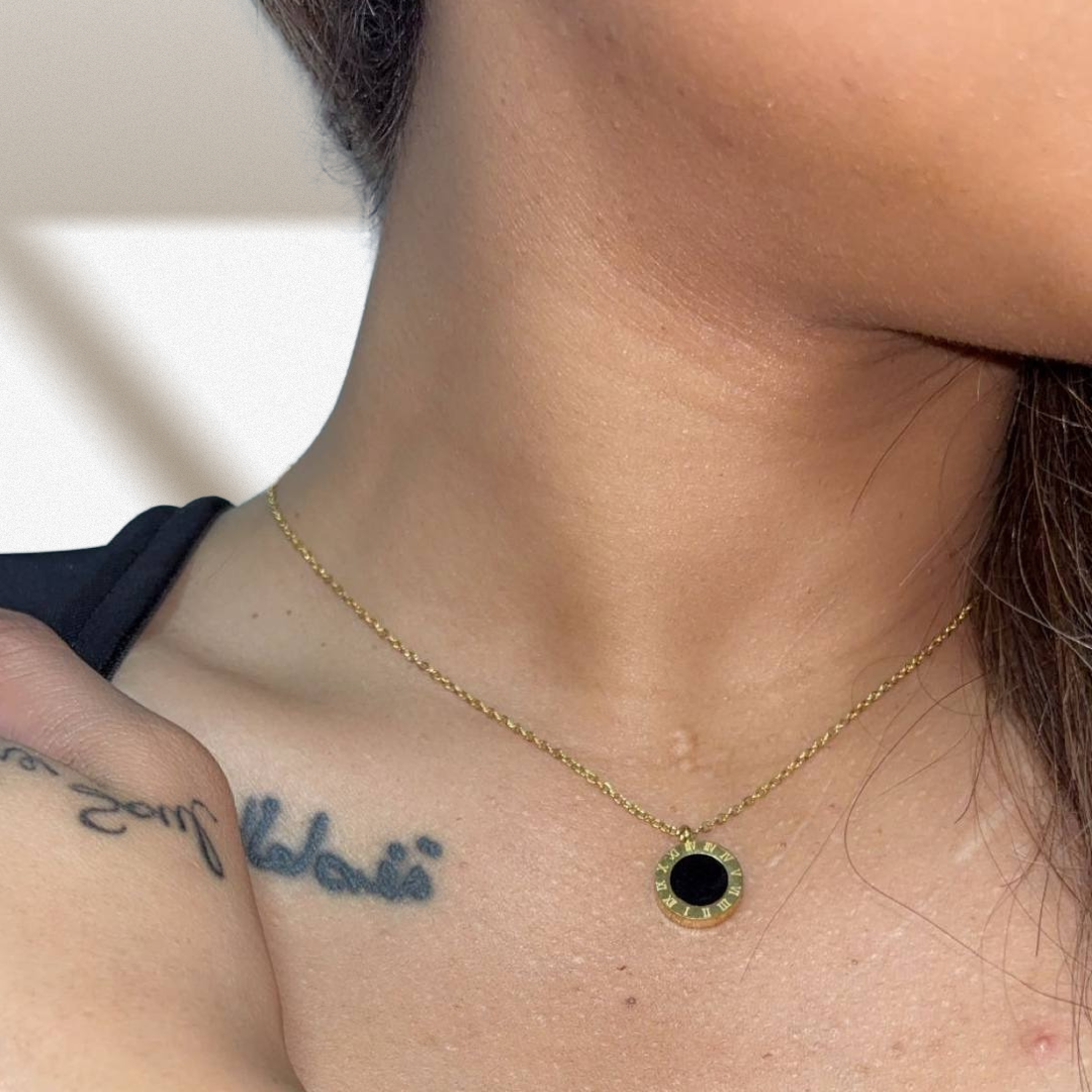 Necklace with a black pendant worn by a person, with tattoos visible on the chest.