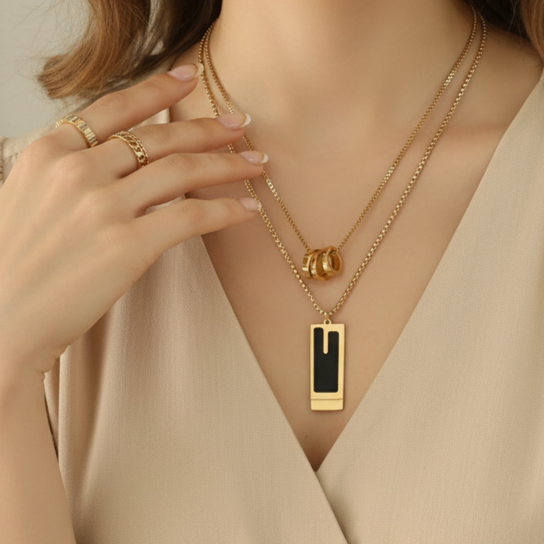 Gold necklace with a pendant worn by a person, with a neutral background