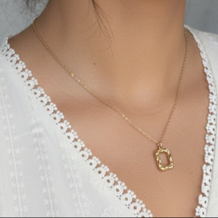 Close-up of a woman wearing a gold necklace with a white lace top.