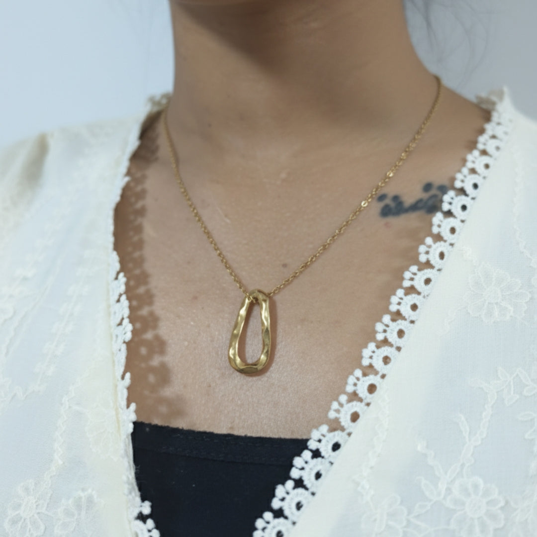Gold necklace worn by a person with a white lace garment