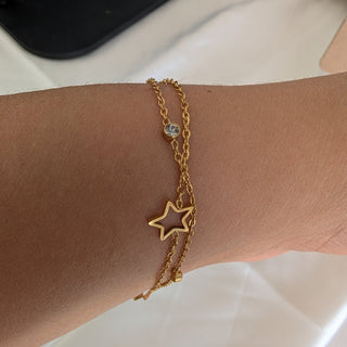Gold star bracelet on a wrist with a neutral background