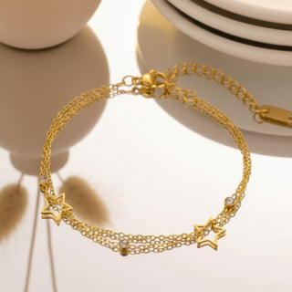 Gold bracelet with star charms on a reflective surface