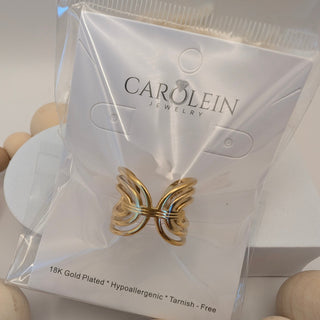 Gold butterfly earring in a Carolein jewelry packaging with wooden beads in the foreground.