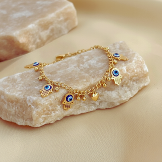 Gold bracelet with charms on a stone surface