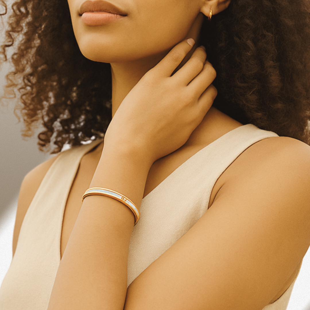 Woman wearing a gold bracelet and earring, with a neutral background