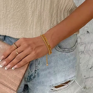 Hand wearing gold bracelets with a blurred background