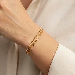 Gold bracelet on a person's wrist with a neutral background