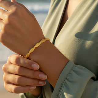 Person wearing a yellow braided bracelet on a blurred natural background