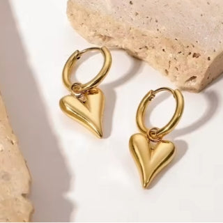 Gold heart-shaped earrings on a light background