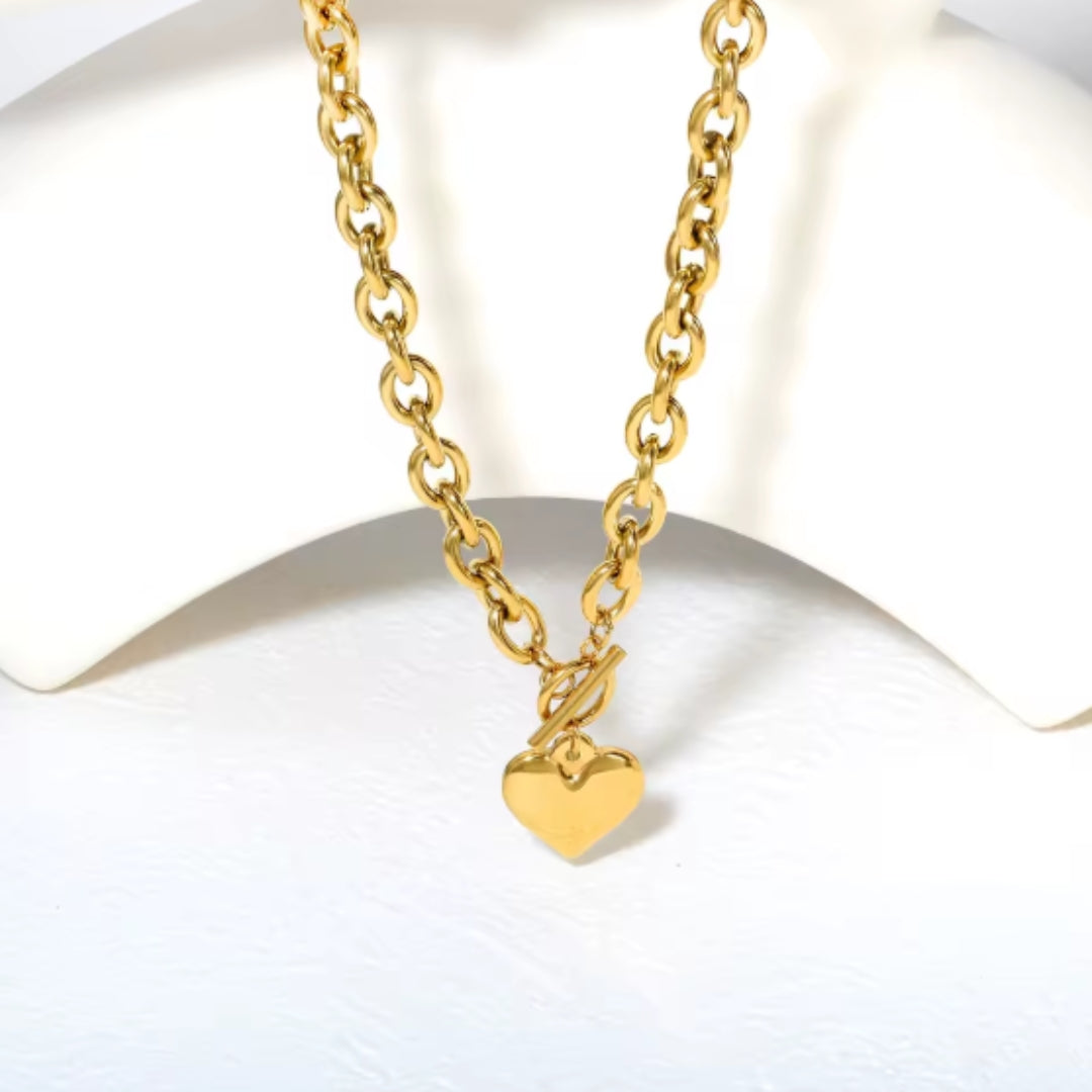 Gold necklace with a heart-shaped pendant on a white background