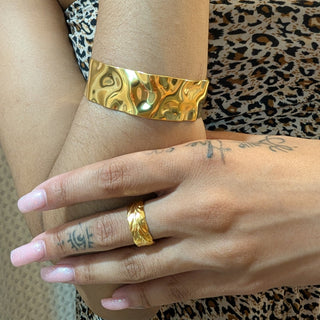 Gold bracelet and ring on a wrist with leopard print fabric in the background