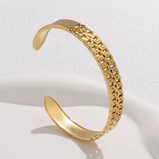 Gold bracelet with intricate design on a light gray background
