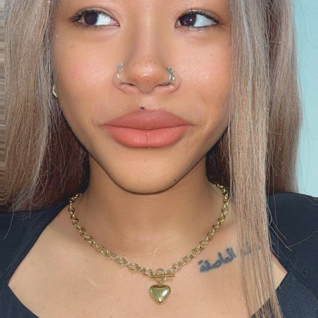 Close-up of a person with a gold chain necklace and heart pendant.