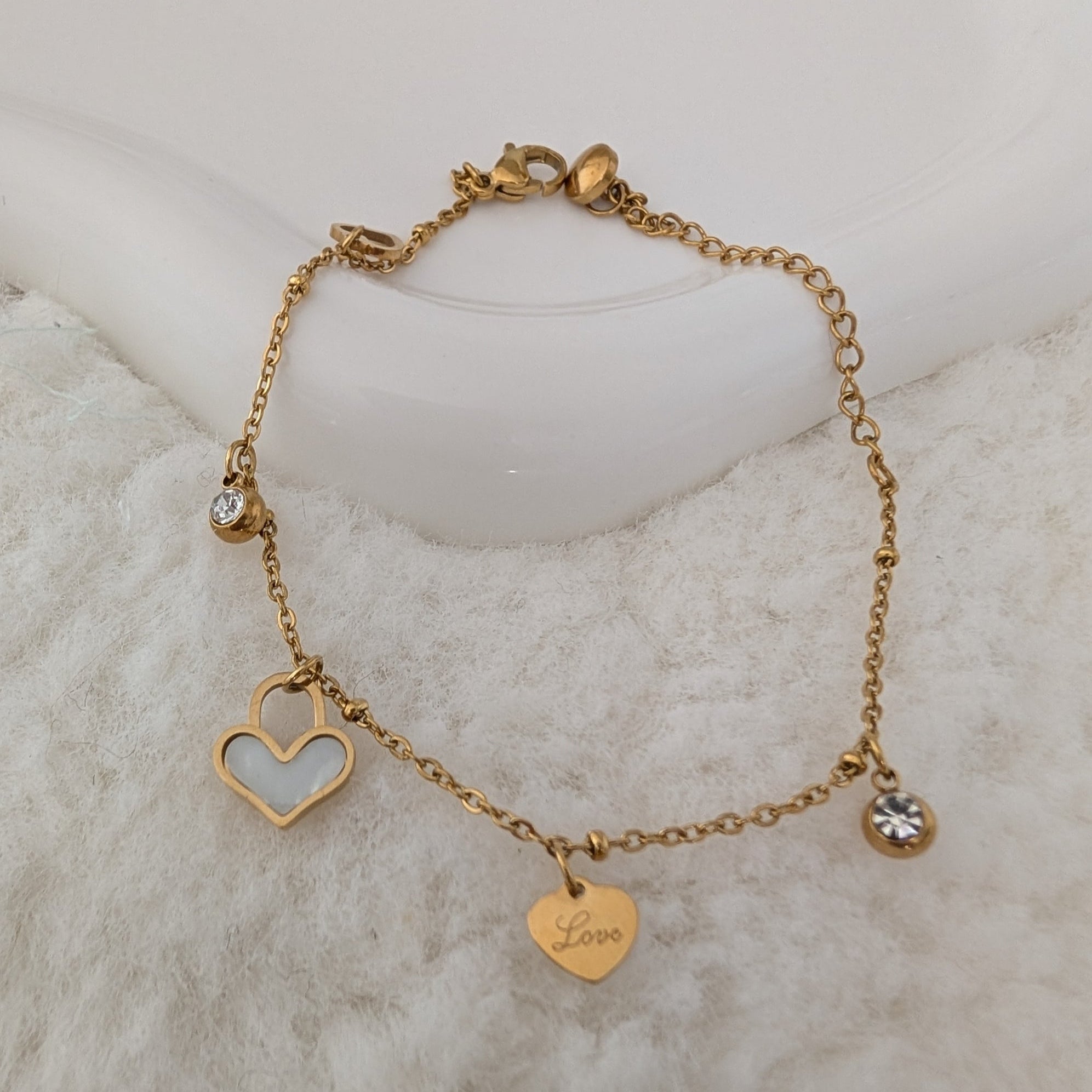 Gold bracelet with heart-shaped charms on a marble surface