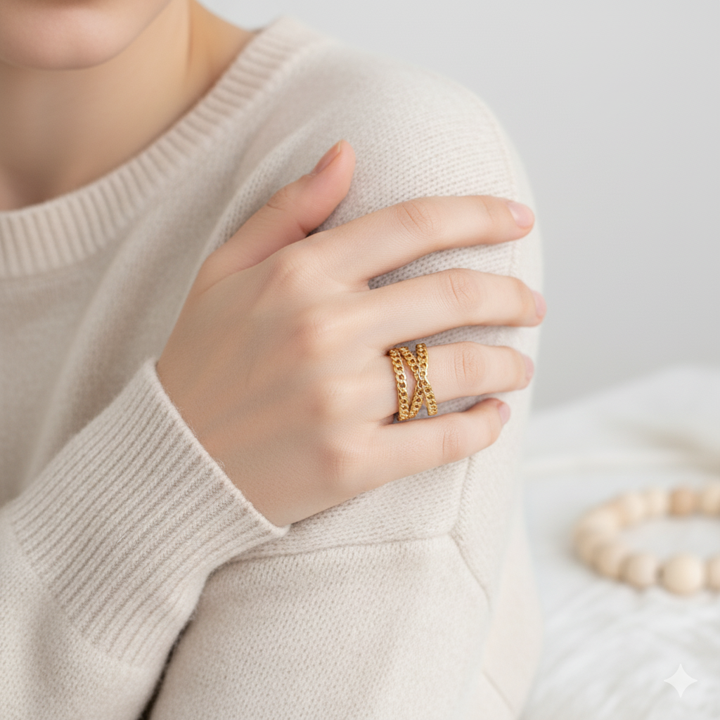 Person wearing a beige sweater with a gold ring on a light background