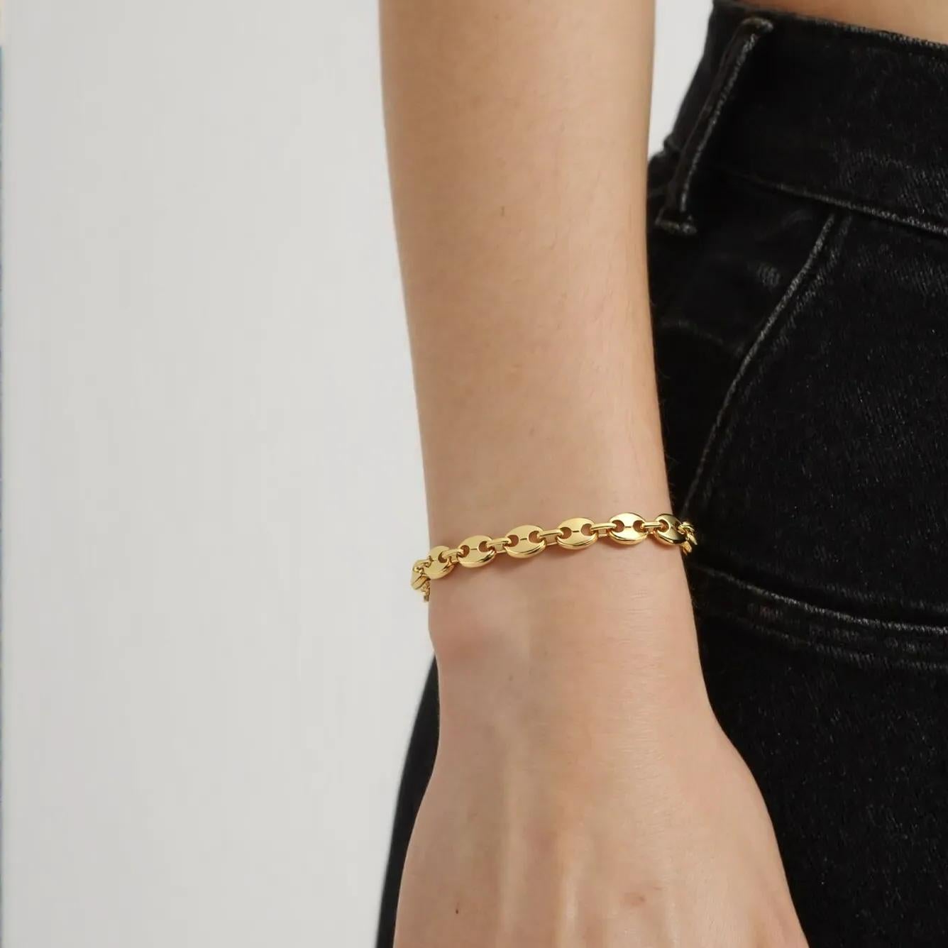 Gold bracelet on a wrist with a plain background