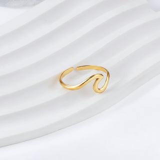 Gold ring with a wavy design on a white fabric background