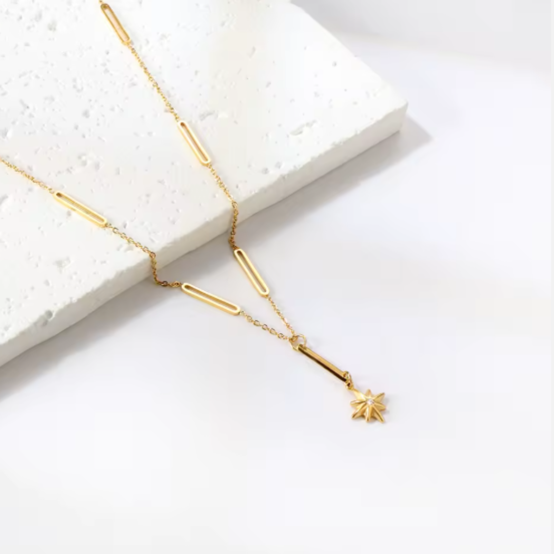 Gold necklace with a star pendant on a white background
