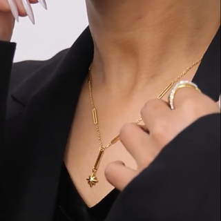 Gold necklace and ring on a person wearing a black outfit