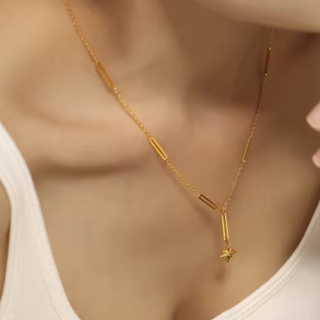 Gold necklace with a star pendant on a blurred background