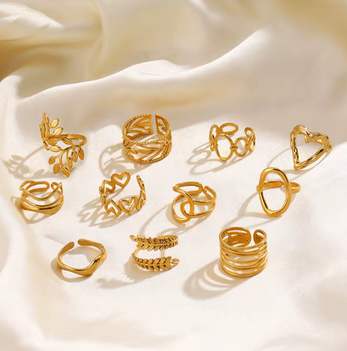 Gold rings with various designs on a beige fabric background