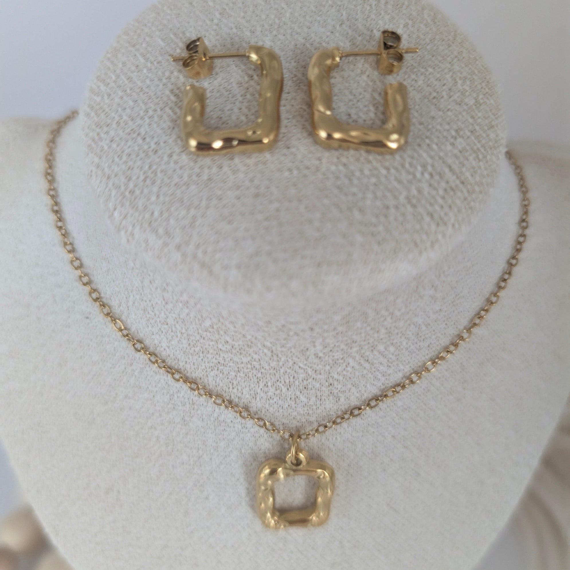 Gold hoop earrings and necklace on a white bust