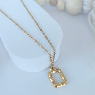 Gold necklace with a unique pendant on a white surface