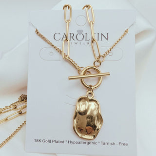 Gold necklace with a pendant on a Carolin Jewelers card.