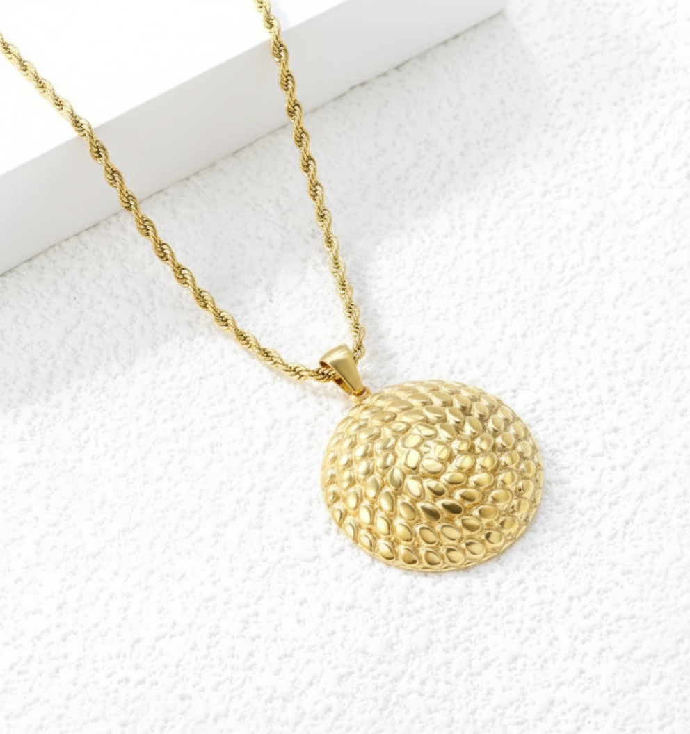 Gold necklace with a textured pendant on a white background