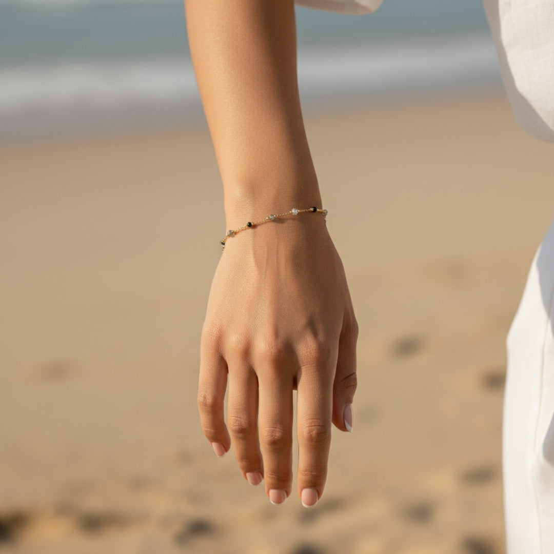 Hand wearing a bracelet on a blurred beach background