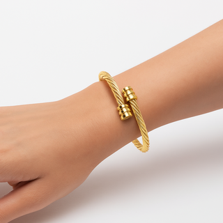 Gold bracelet on a wrist against a light background