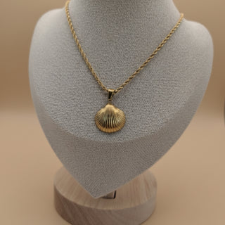 Gold necklace with a shell pendant on a mannequin bust against a beige background