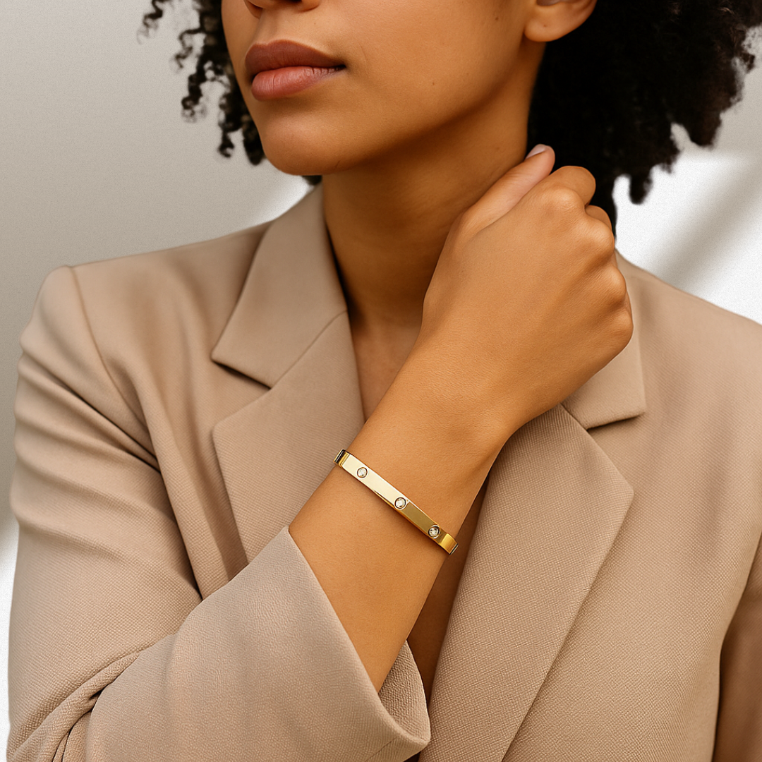 Woman wearing a gold bracelet on a neutral background