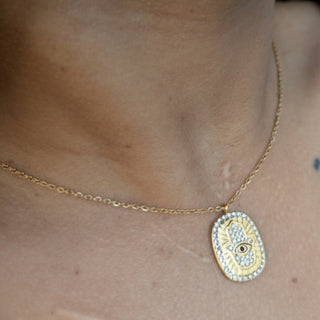 Gold Eye Evil necklace with a decorative pendant on a person's neck.