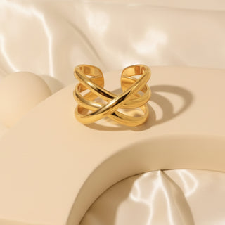 Gold ring with a twisted design on a beige fabric background