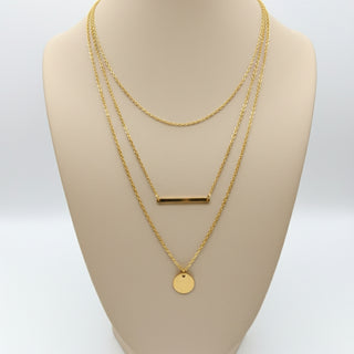 Gold necklaces on a mannequin bust against a white background