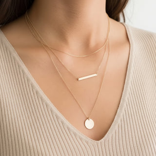 Gold necklaces on a person wearing a beige sweater