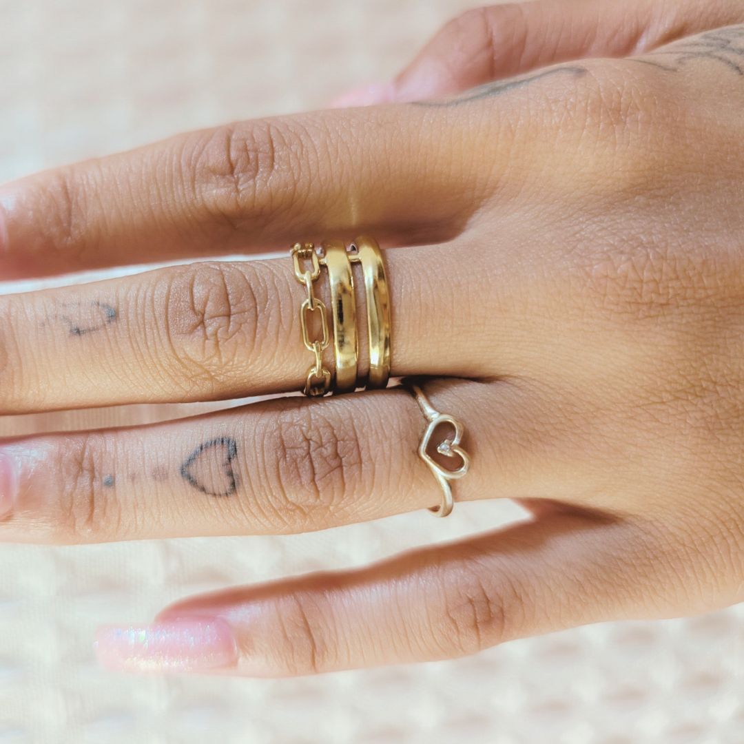 Hand wearing gold rings with a blurred background