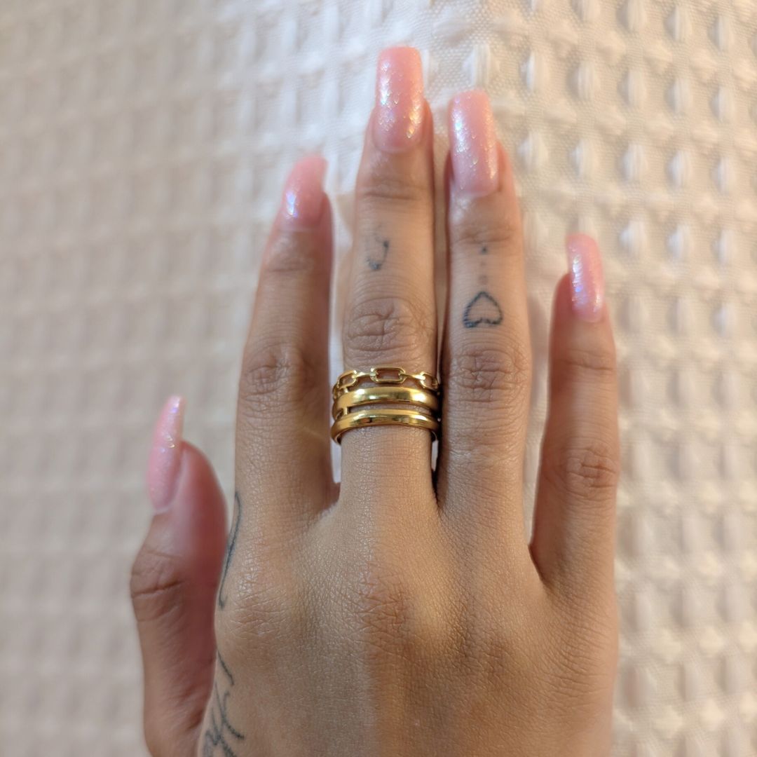 Hand with gold rings on a textured surface