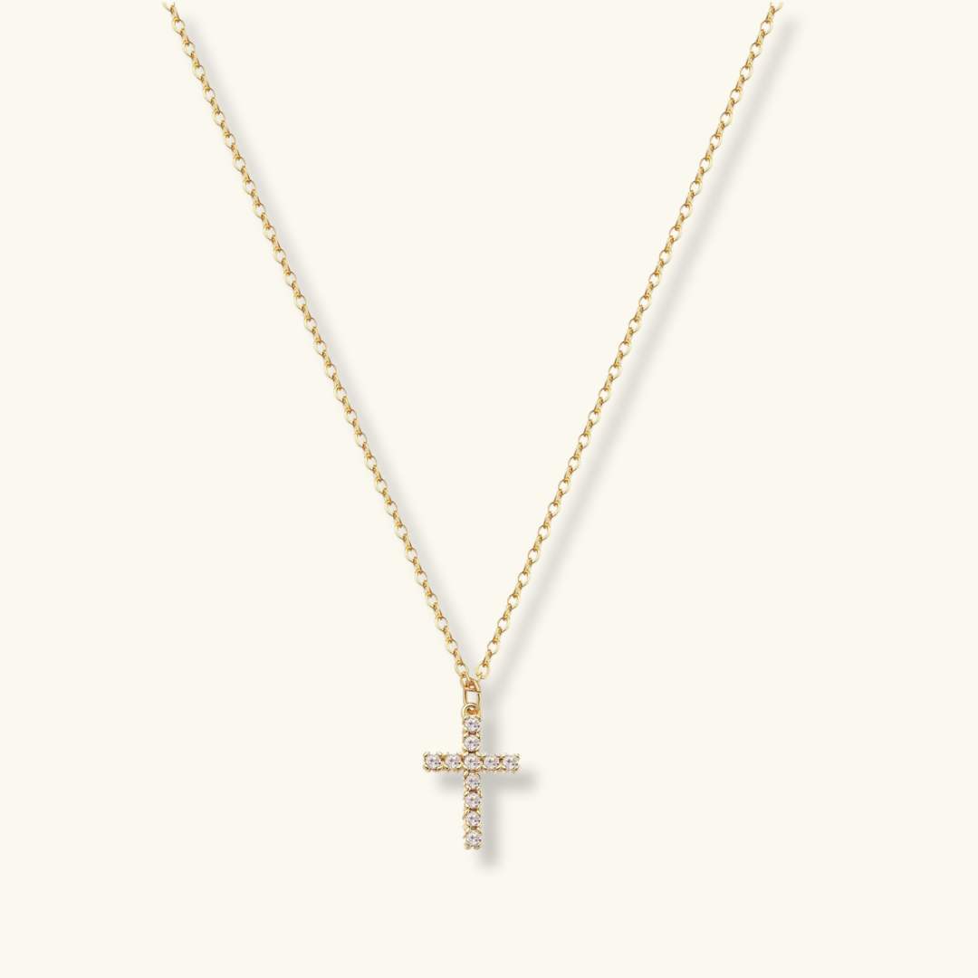 A gold-plated cross pendant necklace with a chain and cubic zirconia inserts, displayed against a white background.
