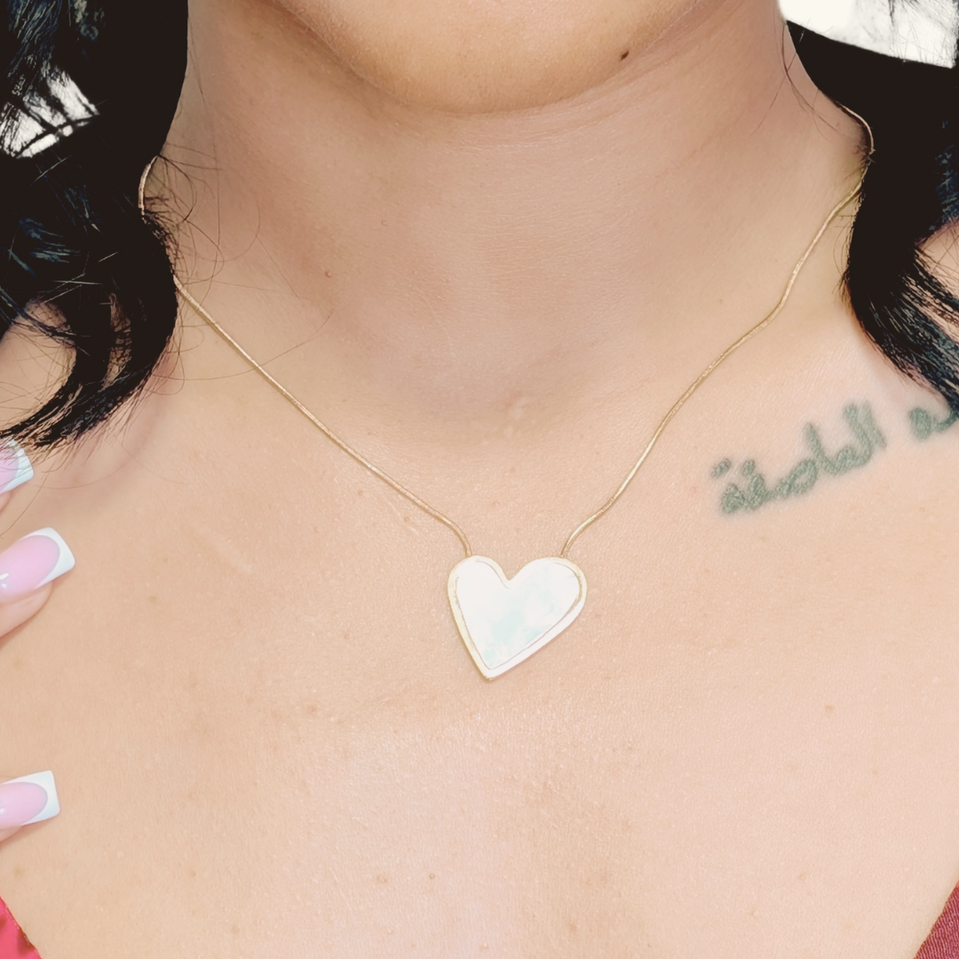 Heart-shaped pendant necklace on a person's neck with visible tattoo