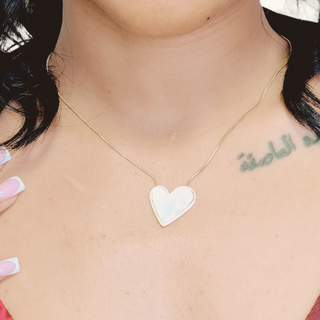 Heart-shaped pendant necklace on a person's neck with visible tattoo