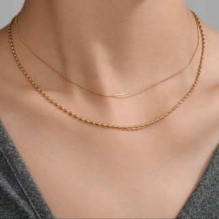 Gold necklace on a mannequin with a gray background
