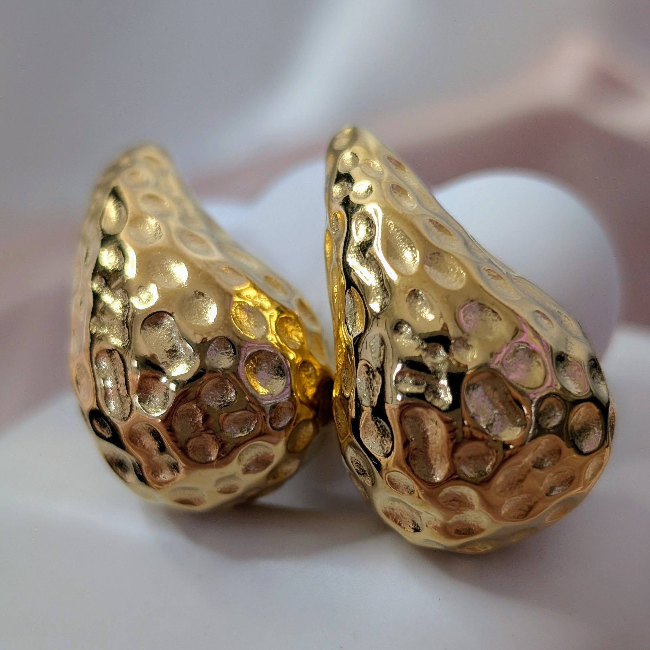 Pair of gold earrings on a white surface