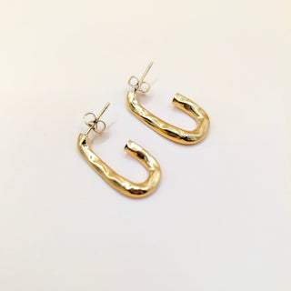 Gold hoop earrings on a light beige background